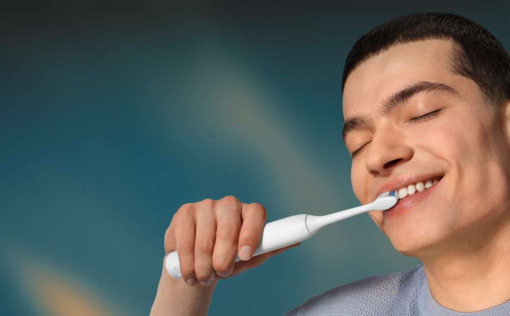 Grafika przedstawiająca zbliżenie na twarz mężczyzny myjącego zęby szczoteczką soniczną.