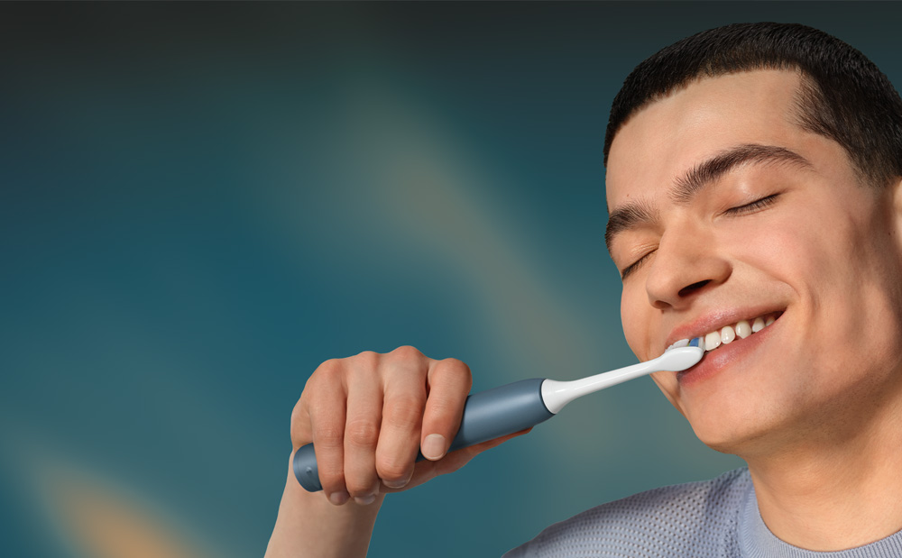 Grafika przedstawiająca zbliżenie na twarz mężczyzny myjącego zęby szczoteczką soniczną.