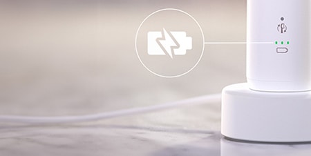 Szczoteczka podłączona do ładowarki. Zbliżenie na ikonę baterii.