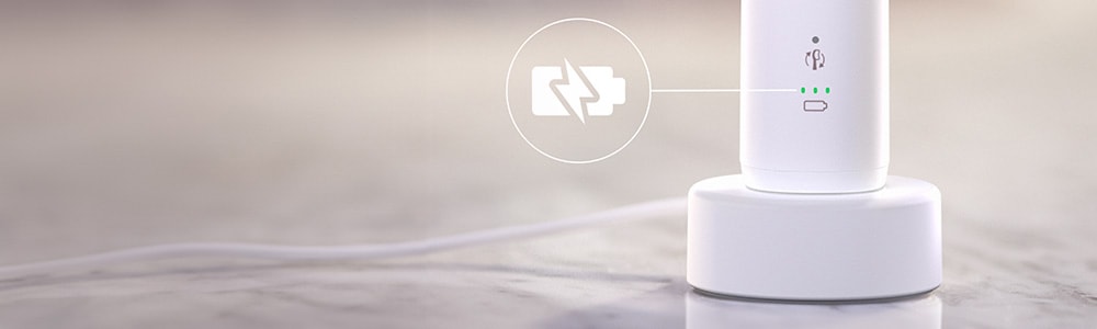 Szczoteczka podłączona do ładowarki. Zbliżenie na ikonę baterii.