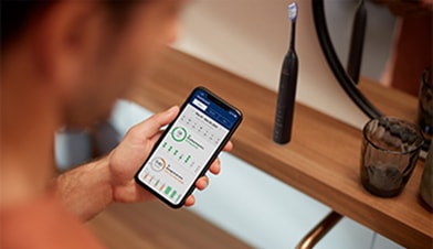 Mężczyzna trzymający w dłoni smartfon z włączoną aplikacją na ekranie.